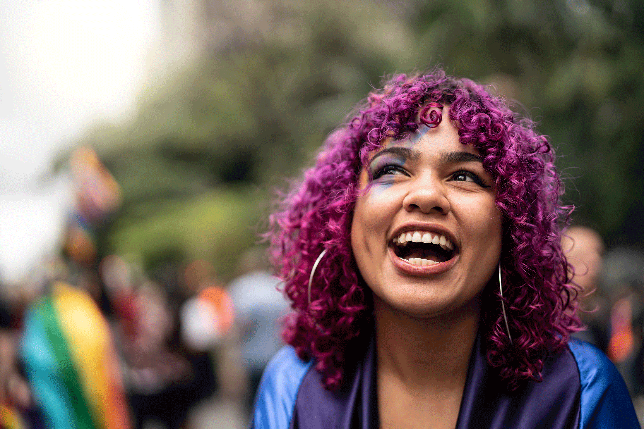 Individual with purple hair smiling looking at the sky