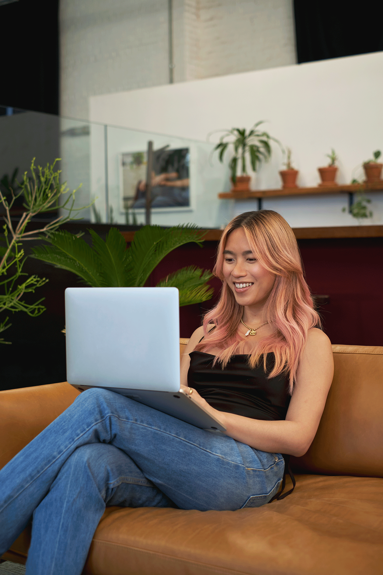 A transfeminine person smiling while working on a laptop